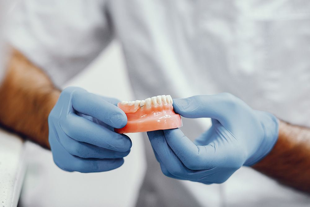 Plastic jaw in the dentist's office. The doctor holds in the hands of dental implants.